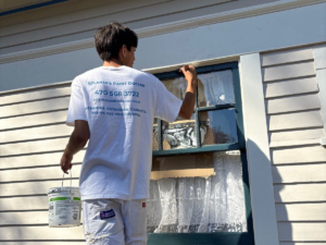 The Hidden Costs of Ignoring Exterior Paint Maintenance - Painter painting window trim with a brush