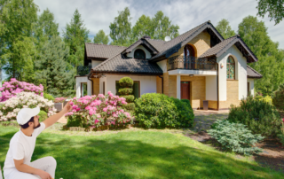 Why Now Is the Perfect Time to Paint - Painter pointing to the house with a roller in his hand.