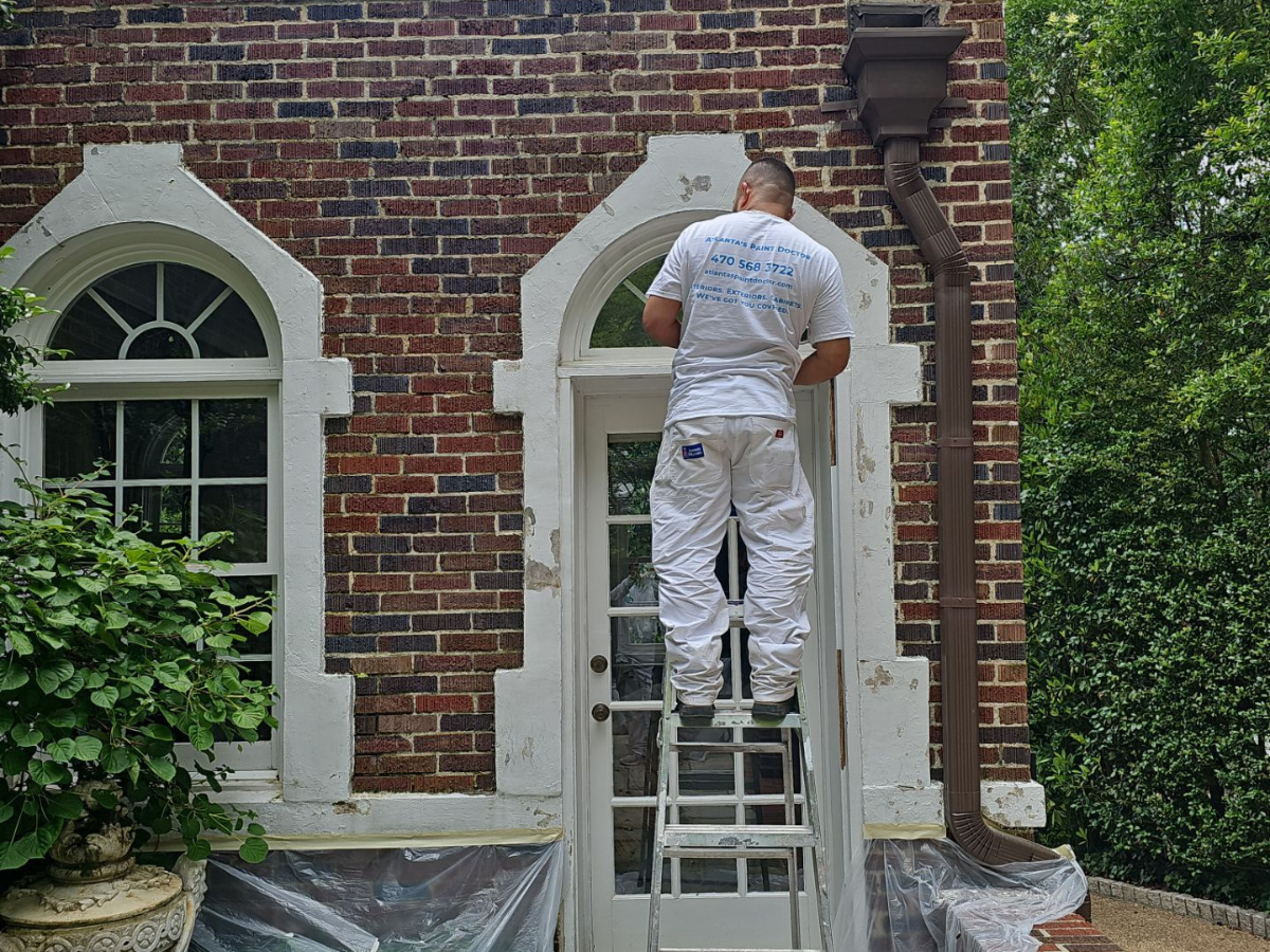 Behind the Scenes: What Makes Atlanta’s Paint Doctor Different - Atlanta's Paint Doctor's crew member standing on a ladder, working on an exterior project.