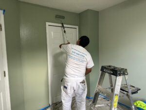 Painter applying green paint to a bedroom wall above a white door in North Atlanta.