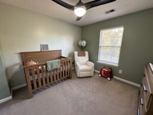 Cozy baby nursery with green walls, a crib, and a rocking chair in North Atlanta.