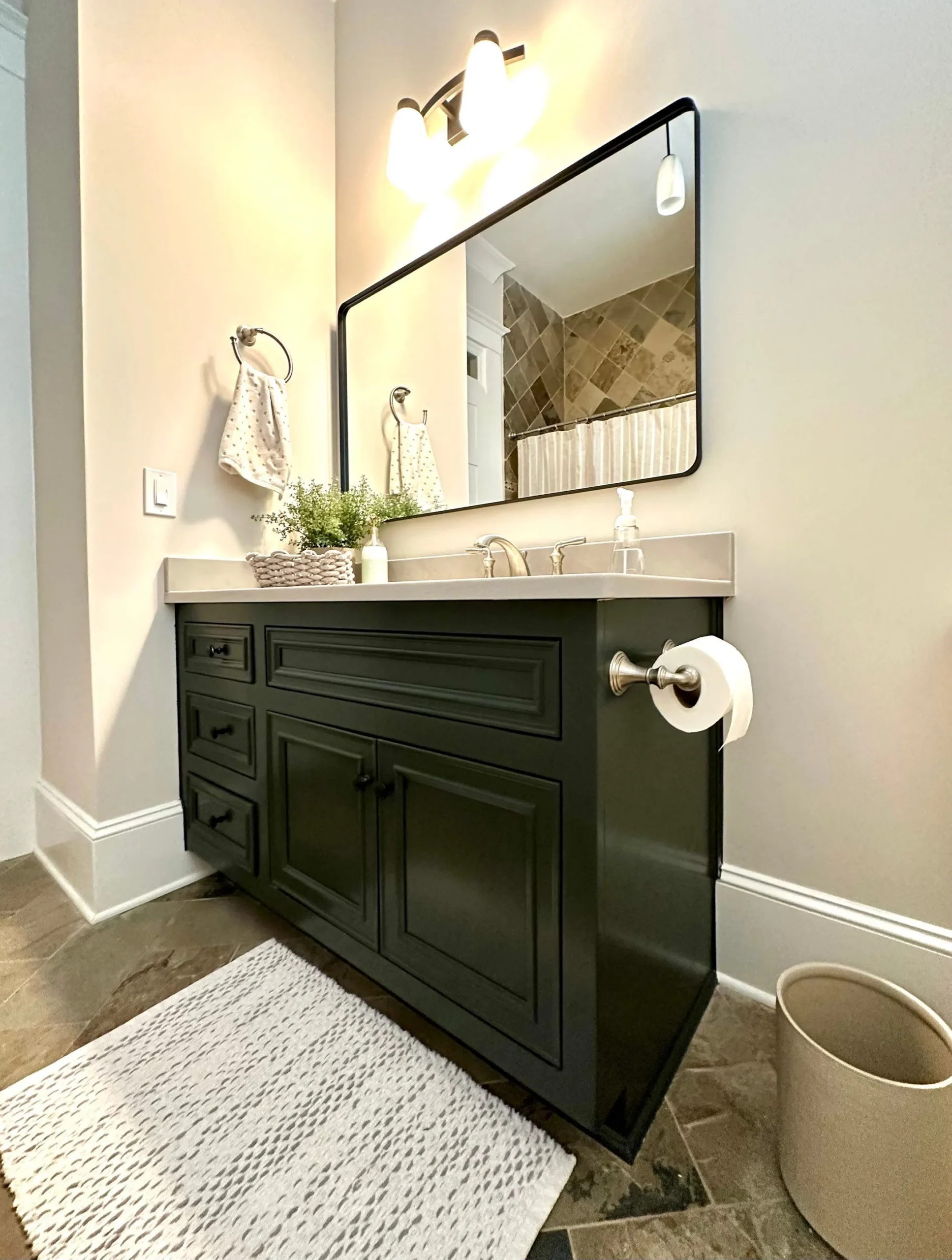 Bathroom Vanity Cabinet Painting in North Atlanta Dark green painted bathroom vanity with a modern mirror and light fixture in North Atlanta.