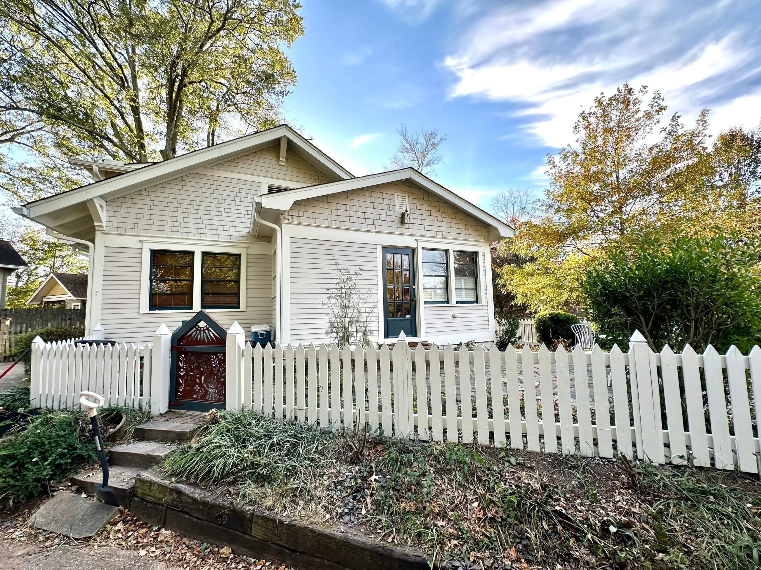 Exterior House Painting North Atlanta Bungalow Front view of a beautifully painted white bungalow house with a picket fence in North Atlanta.