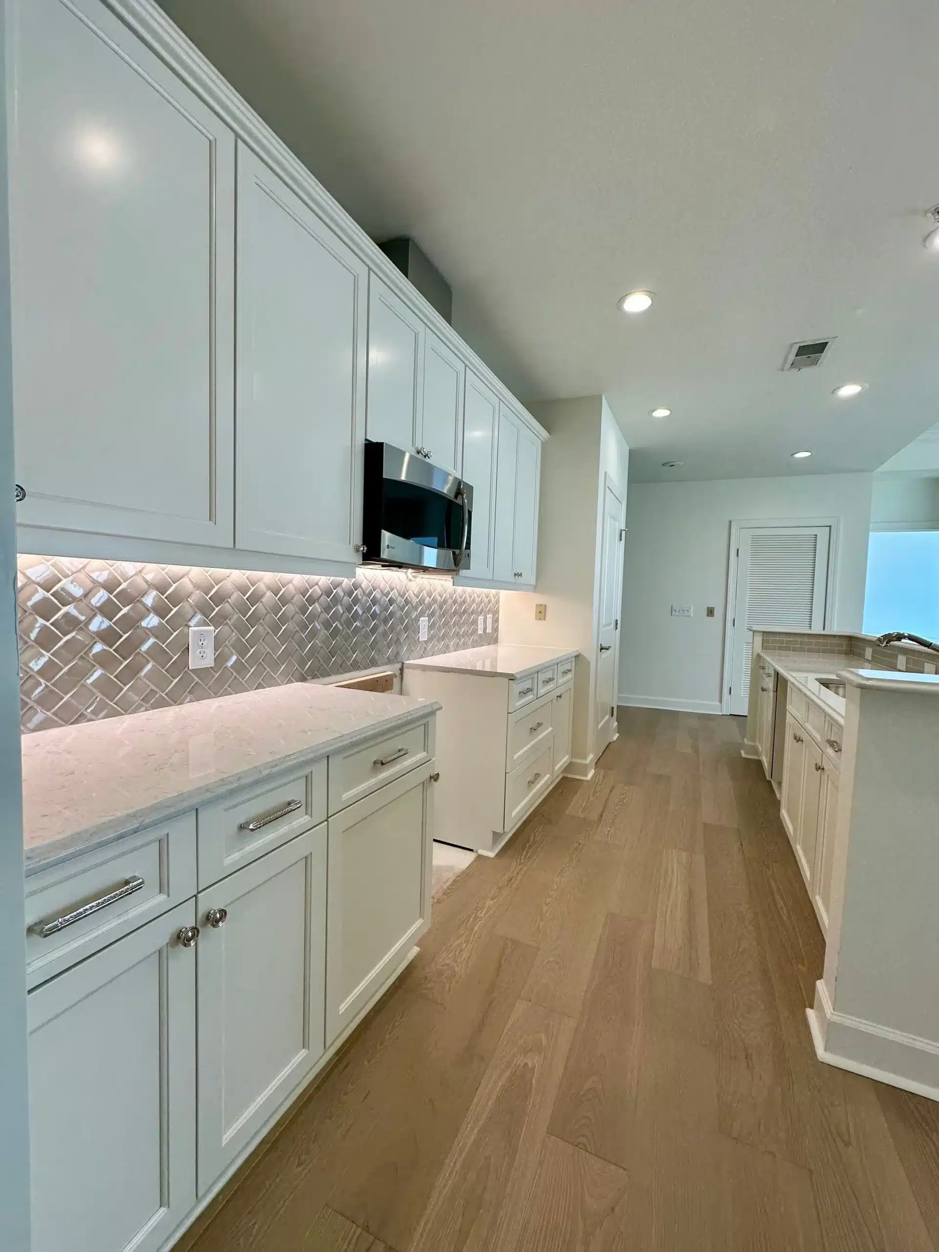 White Kitchen Cabinet Painting in North Atlanta Newly painted white kitchen cabinets with light countertops and backsplash in a North Atlanta home.