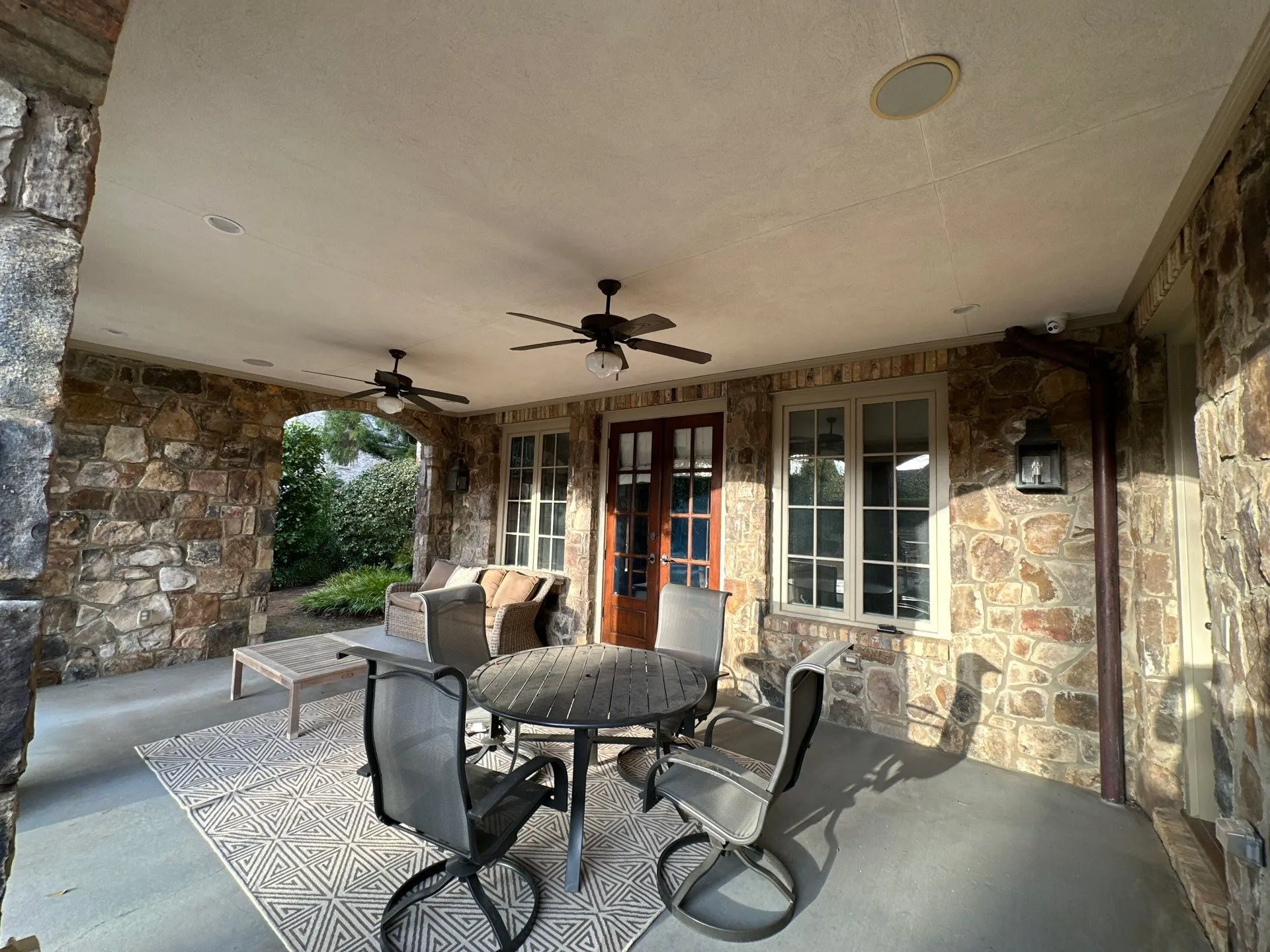 Covered Patio Painting and Staining North Atlanta Spacious covered patio with stone walls and outdoor furniture in a North Atlanta home.