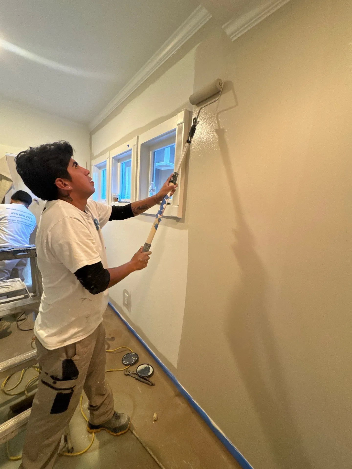 Residential Interior Painting North Atlanta Painter using a roller to paint an interior wall in a home, providing residential painting in North Atlanta.