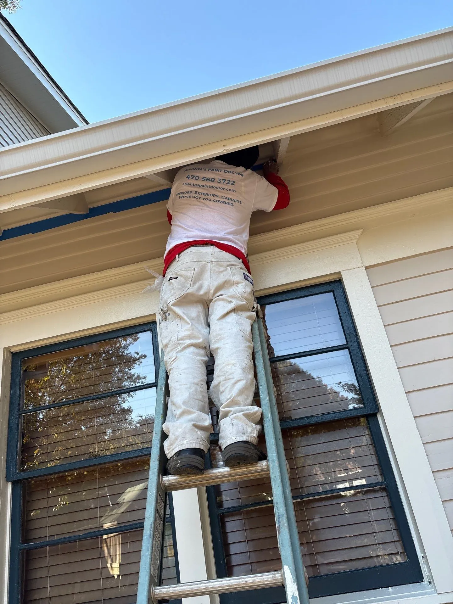 Exterior Painting Services in North Atlanta Painter on ladder preparing exterior for painting services in North Atlanta