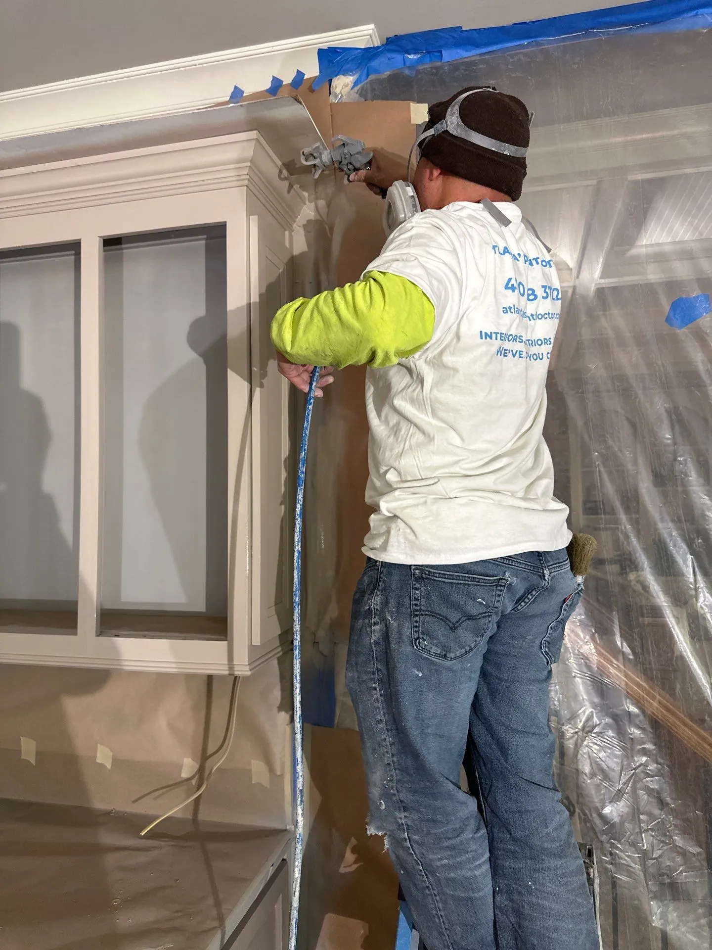 Cabinet Painting Services North Atlanta Painter using a spray gun to paint kitchen cabinets, offering cabinet painting services in North Atlanta.