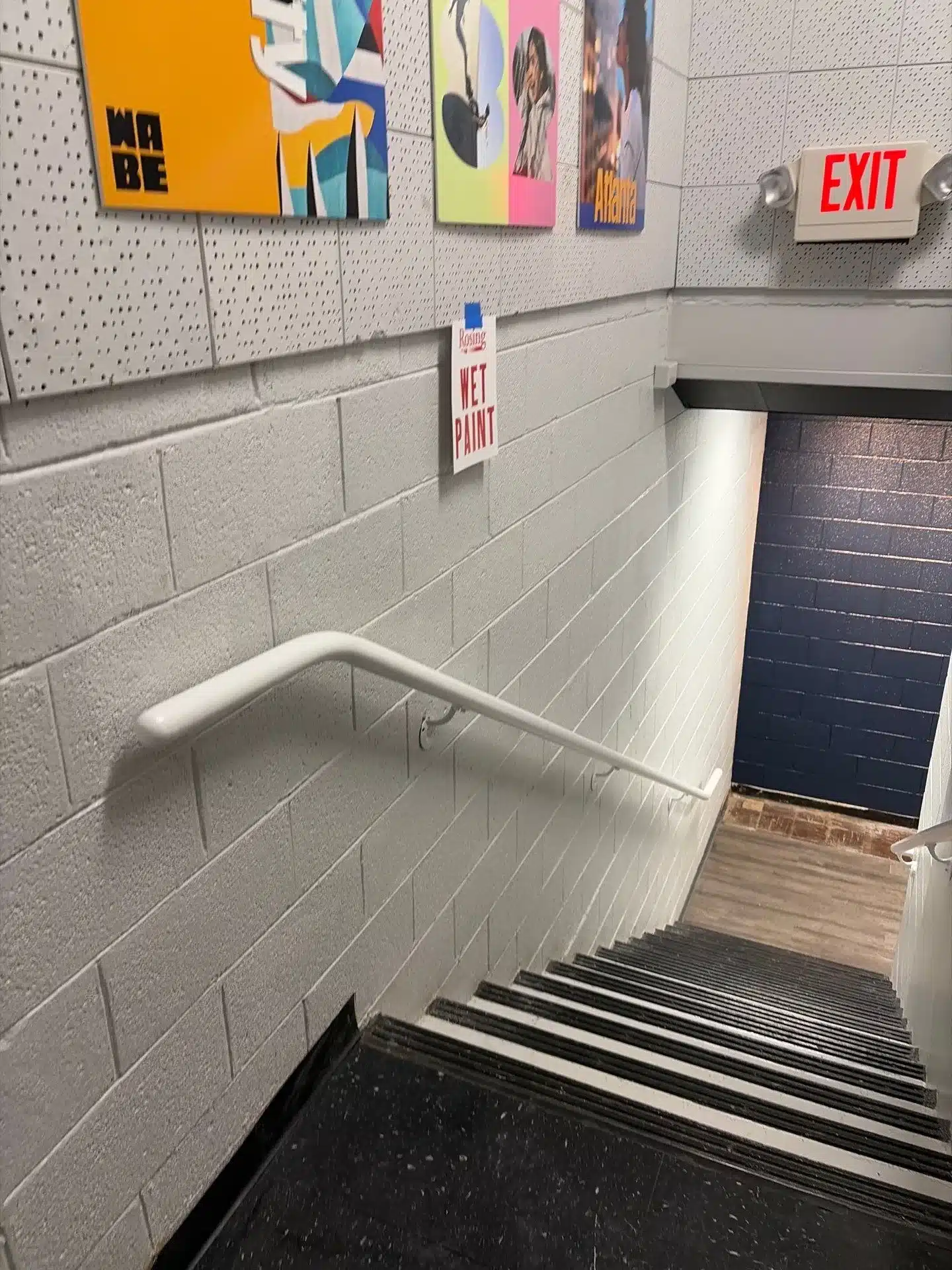 Commercial Stairwell Interior Painting Light gray painted cinder block walls in commercial stairwell with white handrail and dark navy painted door frame.