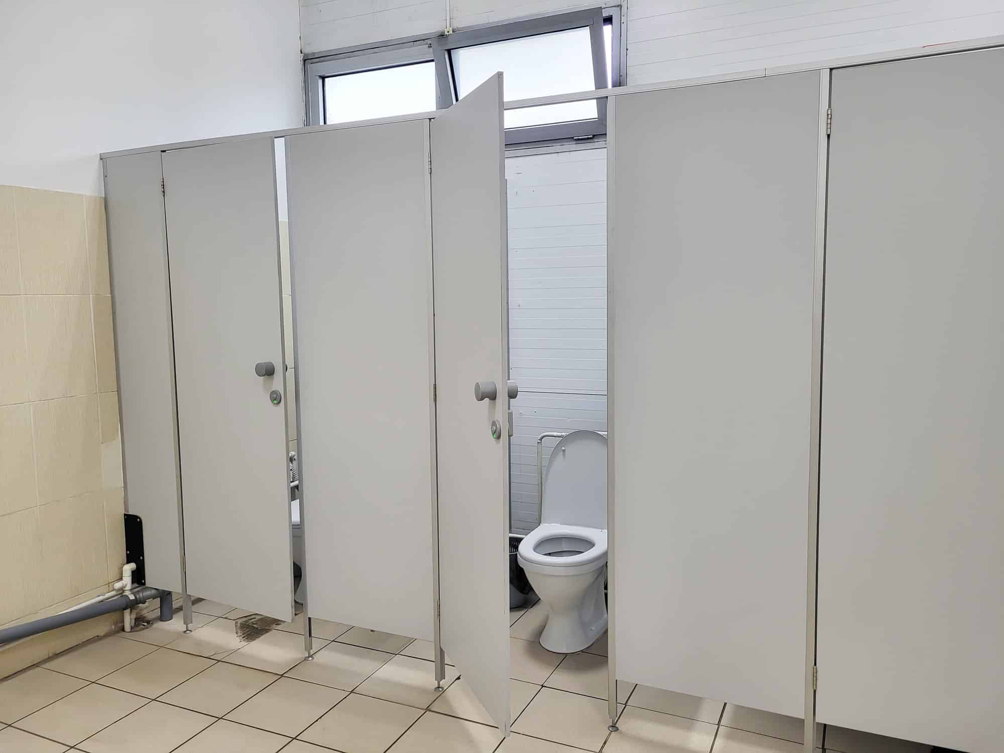 Grey public toilet stalls. One door is open