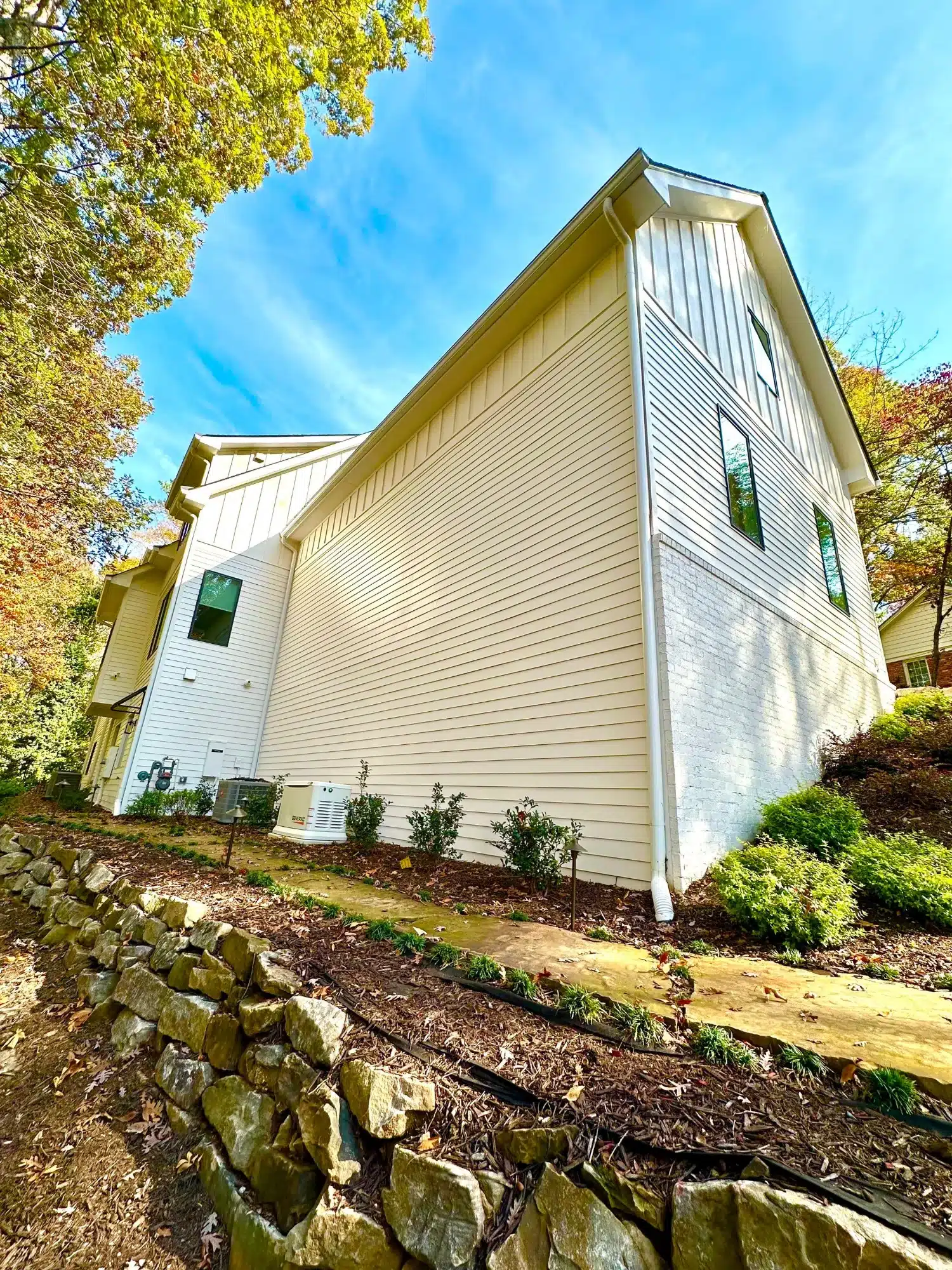 White Painted Residential Exterior Cream-white painted residential siding on contemporary home with white trim, green-framed windows, and stone foundation in