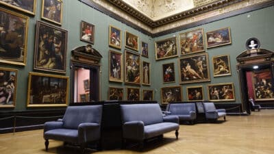 Gallery Interior Painting Soft blue-gray painted gallery interior with classical artwork, wooden floor, and modern seating installation.