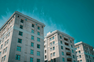 Modern Commercial Building Facade Teal and gray painted multi-story commercial building facade with regular window grid pattern against blue sky.
