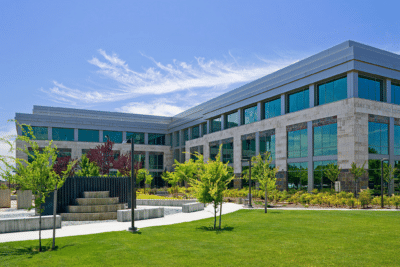 Modern Commercial Building Exterior Modern commercial building with teal-blue painted facade, extensive glass windows, and manicured green lawn landscaping.