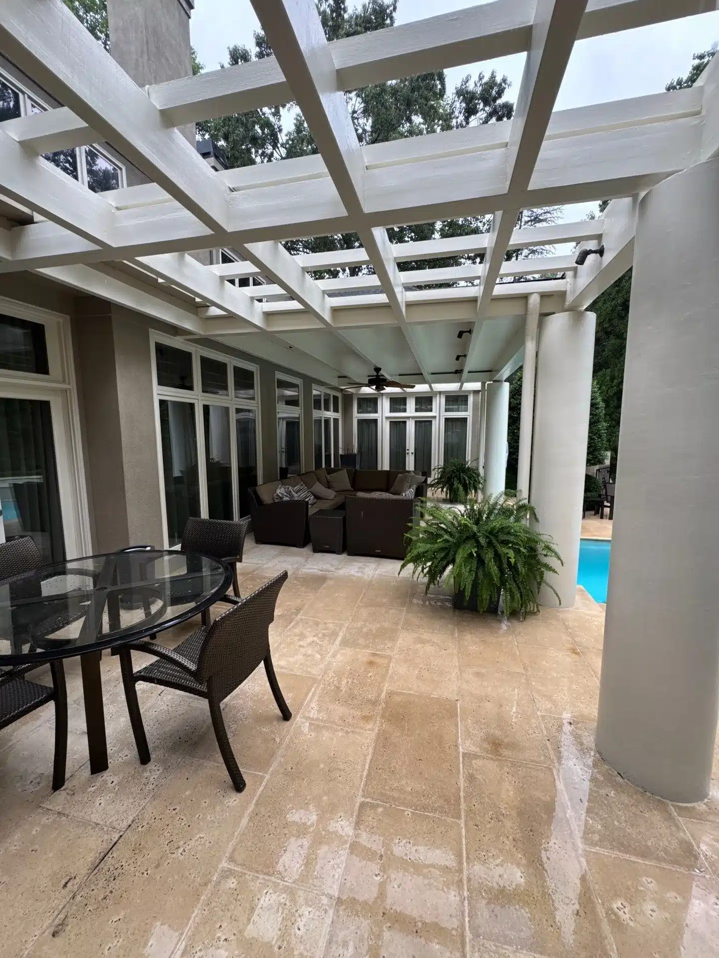Cream Painted Pergola Patio Cream-painted wooden pergola with white lattice beams and skylight panels over stone patio with seating.